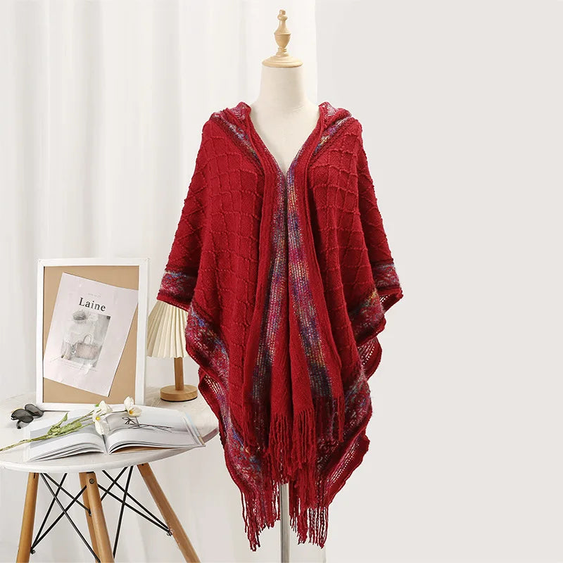Cape poncho rouge bordeaux en maille à capuche, longues franges, disposée sur un buste
