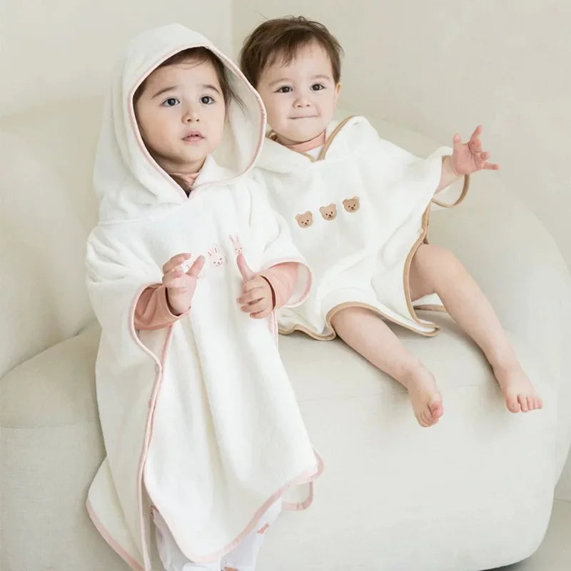 Deux enfants portant le modèle à capuche, coloris écru bordé de rose et de beige