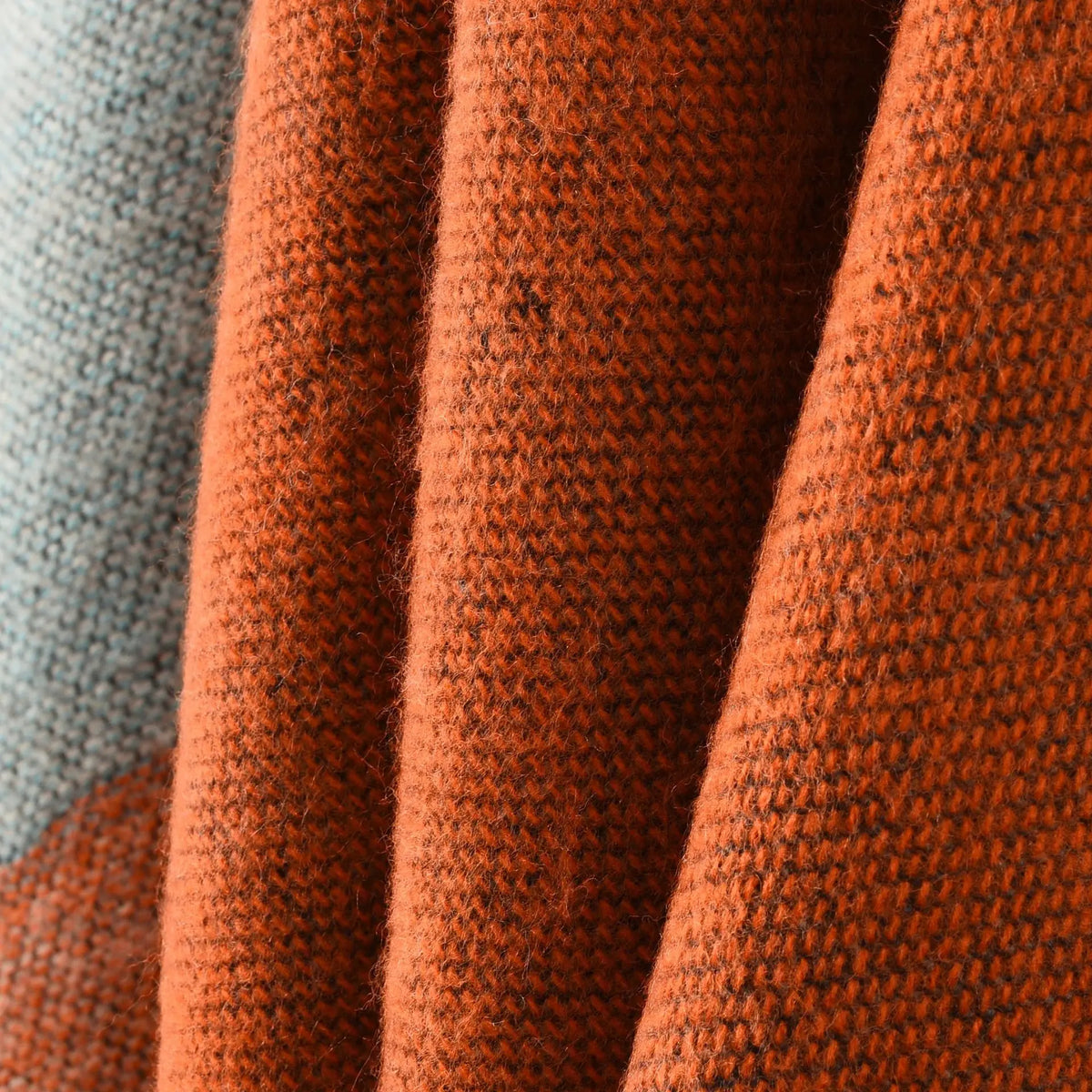 Gros plan sur la maille terracotta et bleu gris, tricot serré et drapé souple