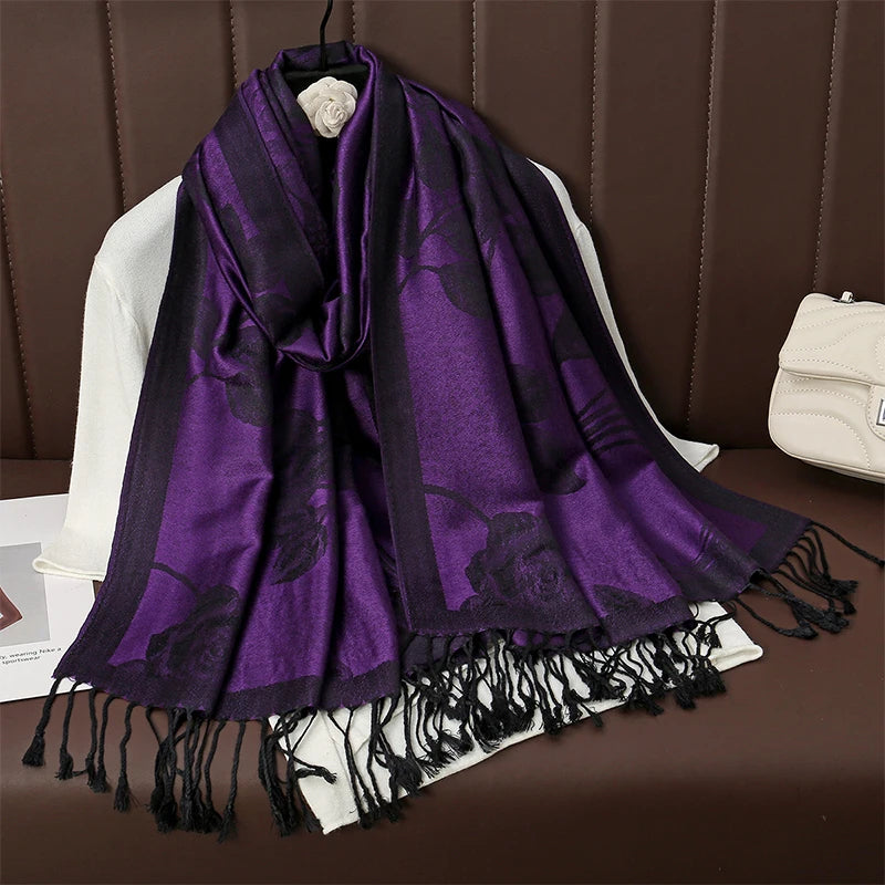 Poncho écharpe violet et noir, roses jacquard et longues franges nouées, sur présentoir