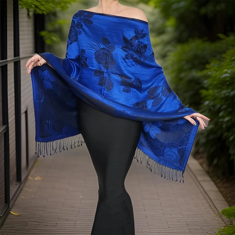 Femme déployant le poncho écharpe bleu à fleurs, bras écartés montrant les franges