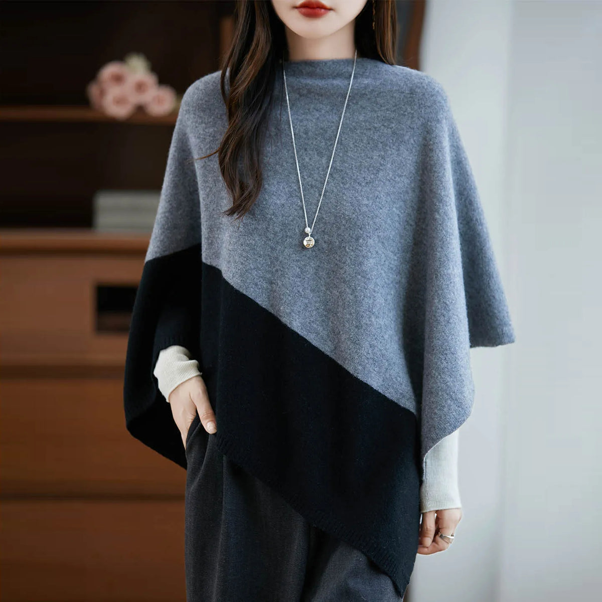Femme portant le poncho gris à panneau noir, col montant et long collier à pendentif