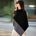 Femme en poncho noir à panneau gris contrasté, col montant et pointe asymétrique, en ville