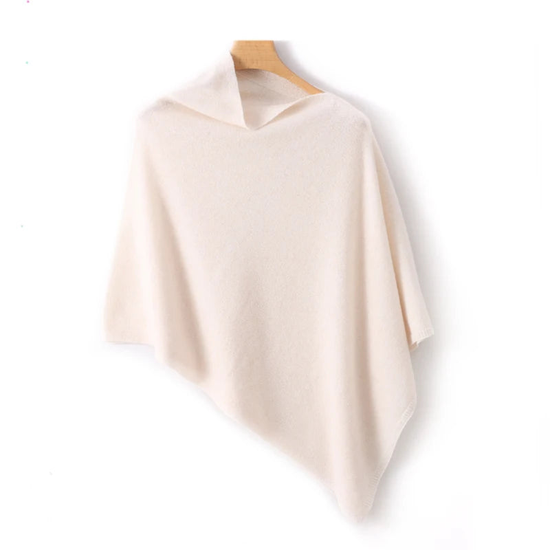 Poncho court écru sur cintre en bois, col bateau discret et bas terminé en pointe