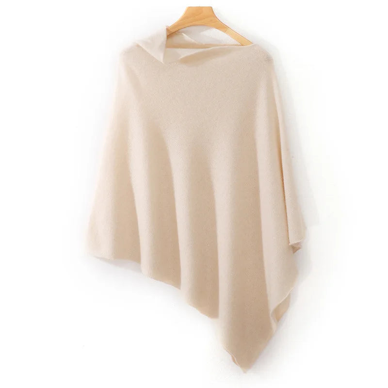 Poncho court beige rosé suspendu à un cintre, col bateau et large pointe descendante