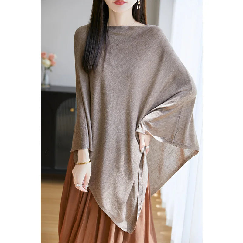 Poncho en maille fine camel porté sur une jupe plissée, pan asymétrique et manche ample