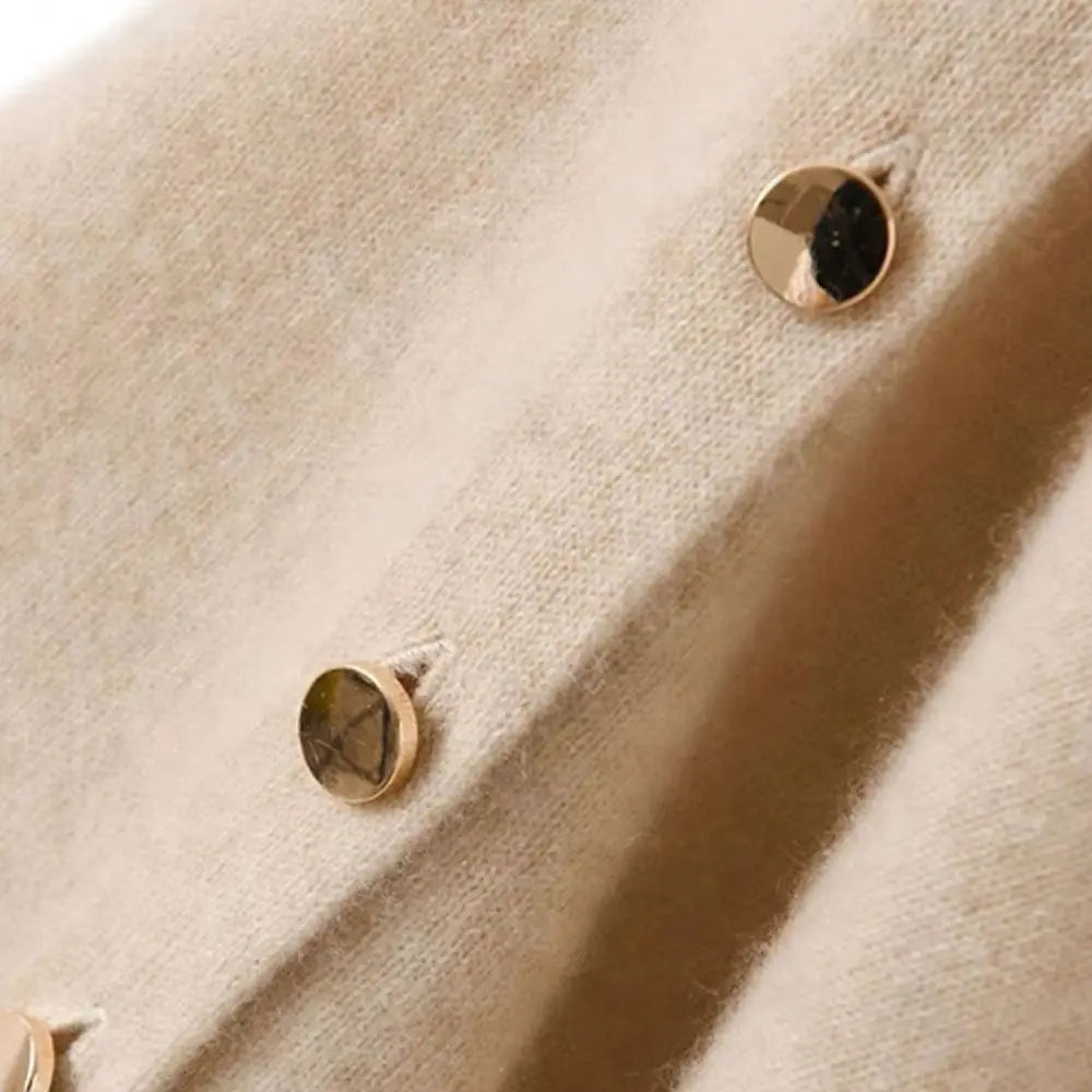 Gros plan sur deux boutons dorés sur la maille fine beige